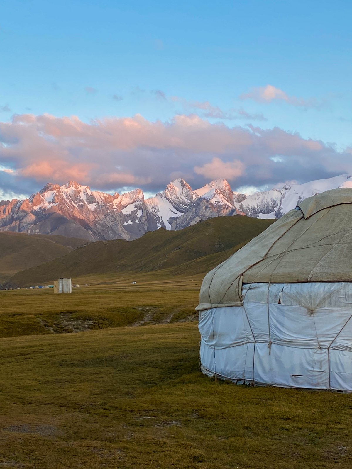 A yurt against a backdrop of snow-capped mountains